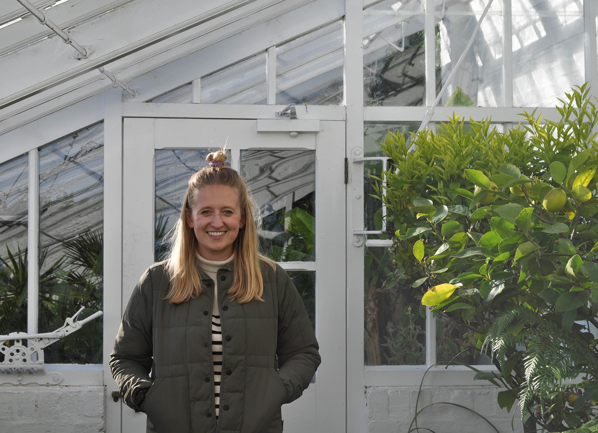 Sophie Tresidder stood in greenhouse next to plants
